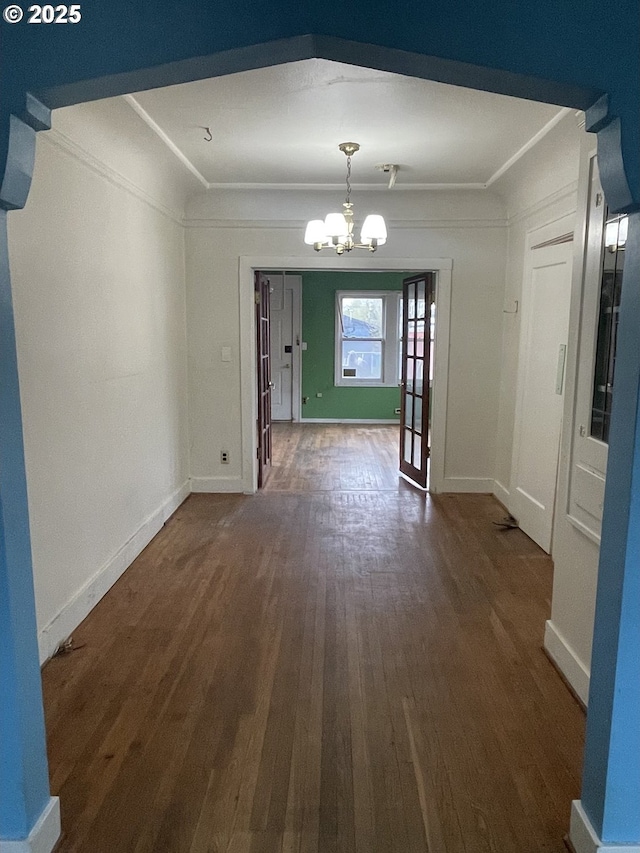 unfurnished dining area featuring ornamental molding, dark hardwood / wood-style floors, and an inviting chandelier