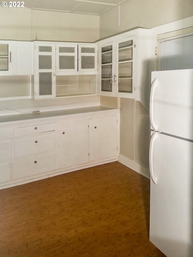 kitchen featuring white cabinets, dark wood-type flooring, and white fridge