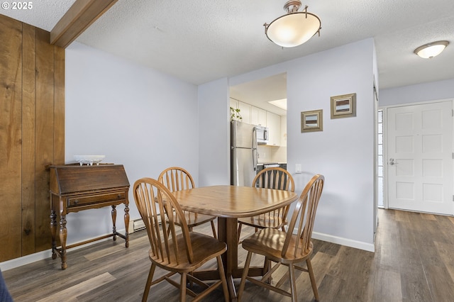 dining space with dark wood finished floors, a textured ceiling, and baseboards