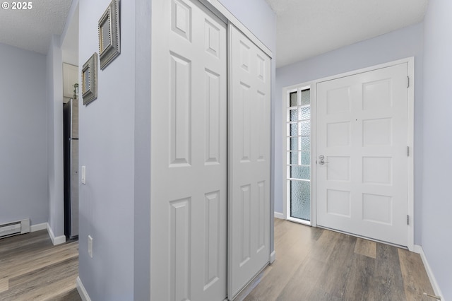 entrance foyer with wood finished floors, baseboards, and baseboard heating