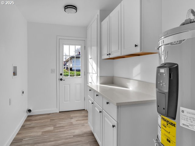 clothes washing area featuring hookup for a washing machine, electric water heater, cabinets, and light hardwood / wood-style floors