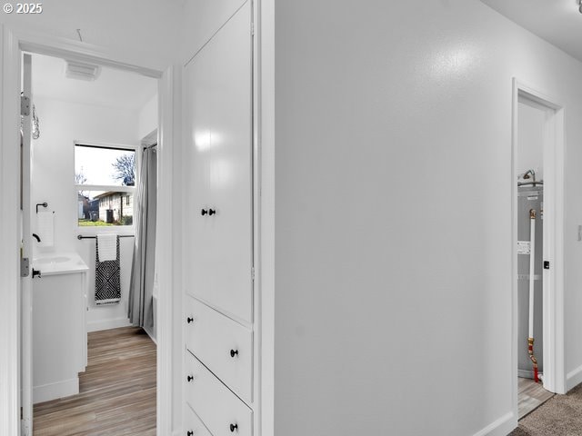 hallway with gas water heater and light hardwood / wood-style floors