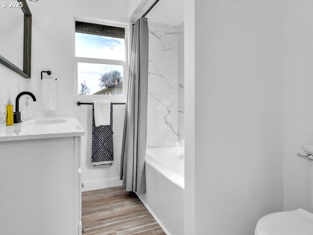 full bathroom with vanity, wood-type flooring, shower / bathtub combination with curtain, and toilet