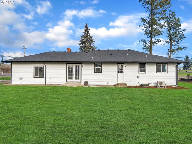 back of property with french doors and a lawn