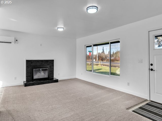 unfurnished living room featuring carpet floors and a wall unit AC