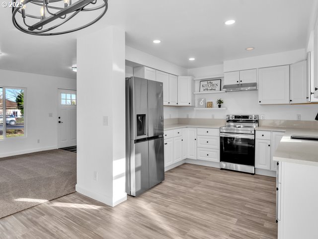 kitchen with sink, white cabinets, a chandelier, stainless steel appliances, and light hardwood / wood-style flooring