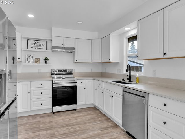 kitchen with sink, light hardwood / wood-style flooring, white cabinets, and appliances with stainless steel finishes