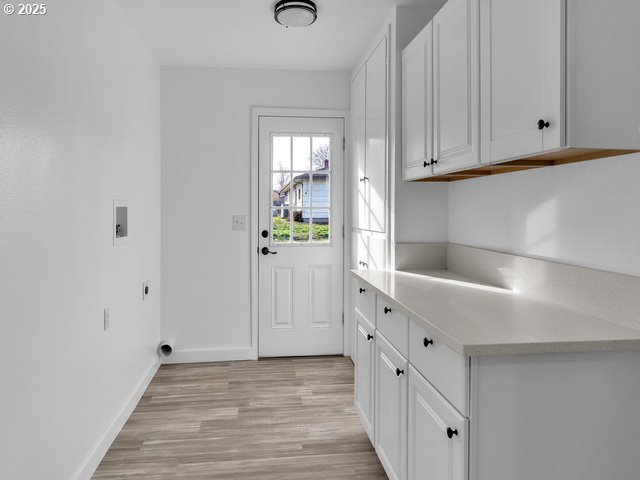 laundry room with electric dryer hookup, hookup for a washing machine, light hardwood / wood-style flooring, and cabinets