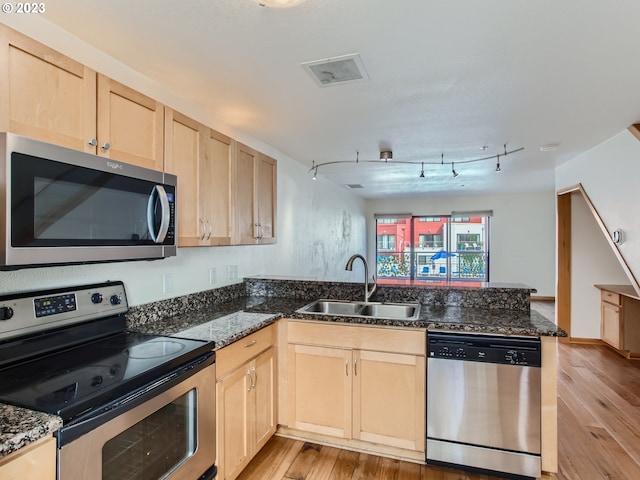 kitchen with sink, light brown cabinetry, light hardwood / wood-style floors, kitchen peninsula, and stainless steel appliances