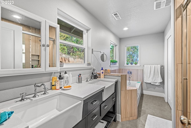 bathroom featuring dual vanity, tile flooring, plenty of natural light, and a textured ceiling