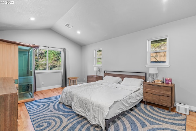 bedroom featuring multiple windows, lofted ceiling, and light wood-type flooring