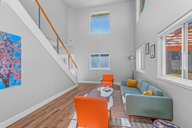 interior space with light wood-type flooring, a high ceiling, and a healthy amount of sunlight