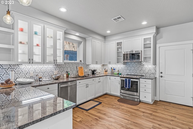 kitchen featuring appliances with stainless steel finishes, white cabinetry, backsplash, and light hardwood / wood-style flooring