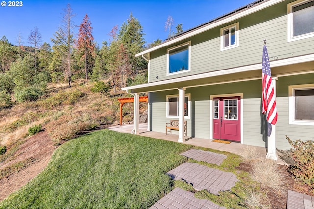 back of property with covered porch and a lawn