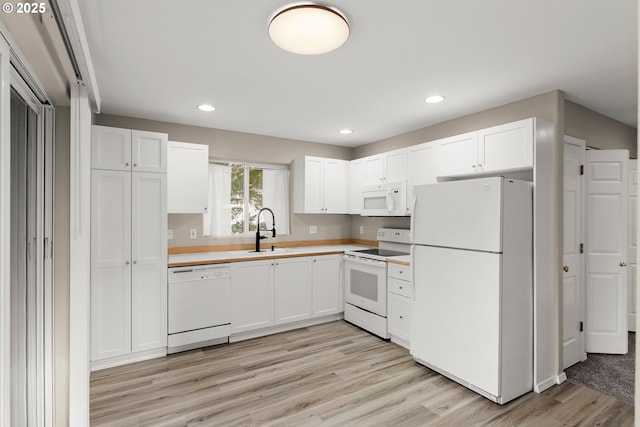 kitchen featuring white appliances, light hardwood / wood-style floors, sink, and white cabinets