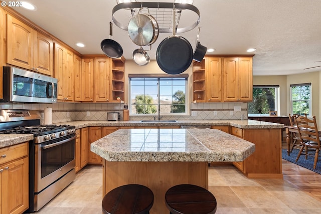 kitchen featuring appliances with stainless steel finishes, a kitchen island, backsplash, and a wealth of natural light