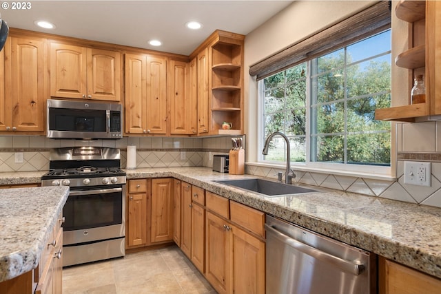 kitchen featuring backsplash, appliances with stainless steel finishes, sink, light tile floors, and a wealth of natural light