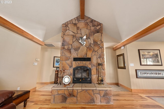 living room featuring vaulted ceiling with beams, light hardwood / wood-style floors, and a fireplace