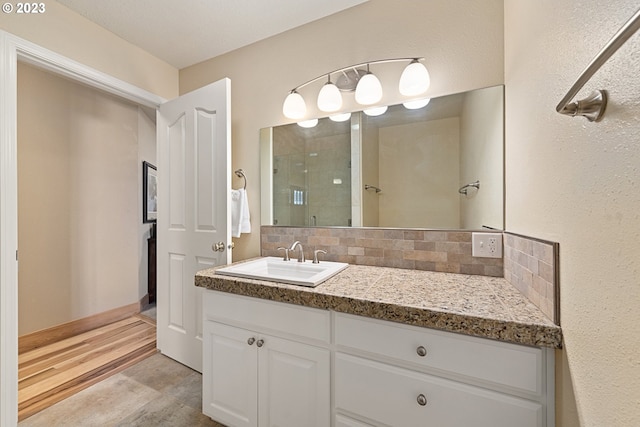 bathroom featuring backsplash, vanity with extensive cabinet space, and hardwood / wood-style flooring