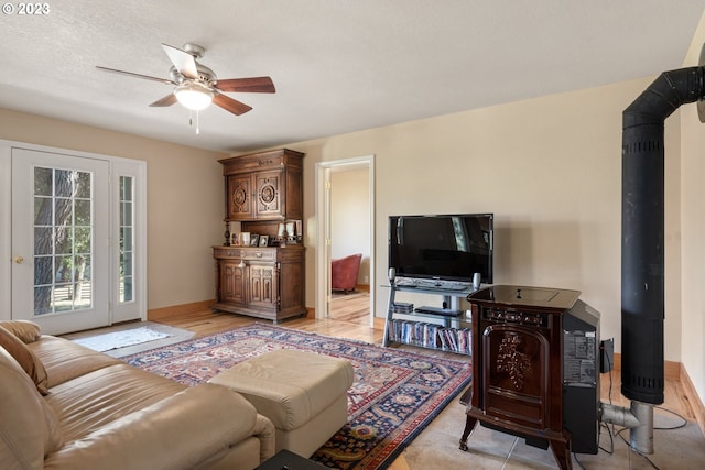 living room featuring a wood stove, ceiling fan, and a textured ceiling