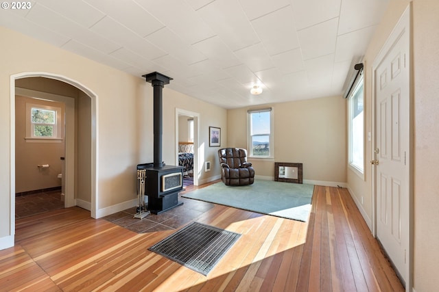 workout room with a wood stove, a wealth of natural light, and light hardwood / wood-style flooring