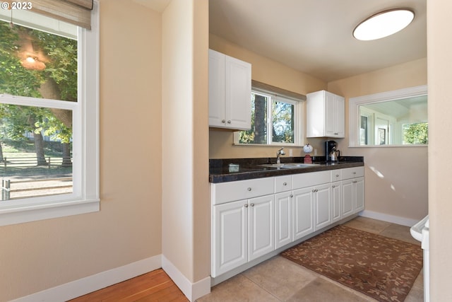 kitchen featuring light tile floors, white cabinetry, and sink