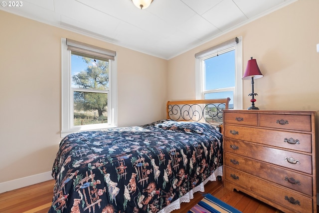 bedroom featuring multiple windows, crown molding, and light hardwood / wood-style flooring