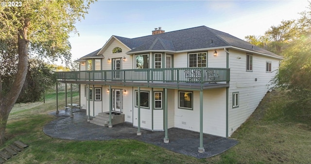 rear view of property featuring a balcony and a lawn