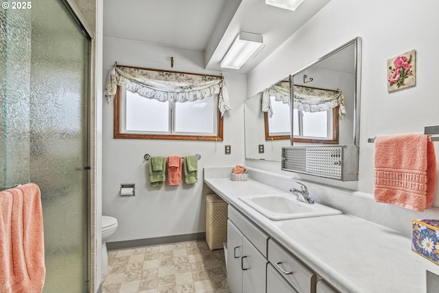 bathroom featuring toilet, a shower stall, baseboards, and vanity