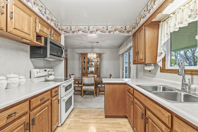 kitchen with light countertops, stainless steel microwave, brown cabinetry, a sink, and double oven range