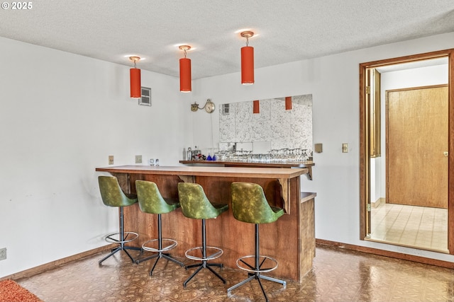 bar with tile patterned floors, baseboards, indoor wet bar, and decorative light fixtures