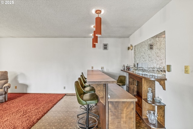 interior space with a textured ceiling and a dry bar