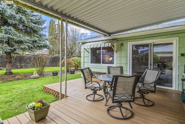 wooden terrace featuring outdoor dining area, fence, and a lawn