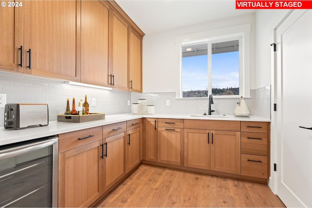 kitchen with wine cooler, sink, light hardwood / wood-style flooring, and tasteful backsplash