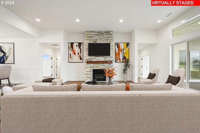 living room with a stone fireplace and hardwood / wood-style flooring