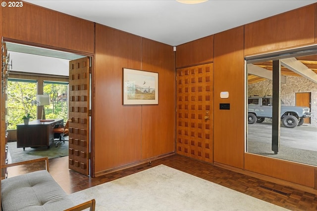 interior space featuring dark parquet floors and wood walls