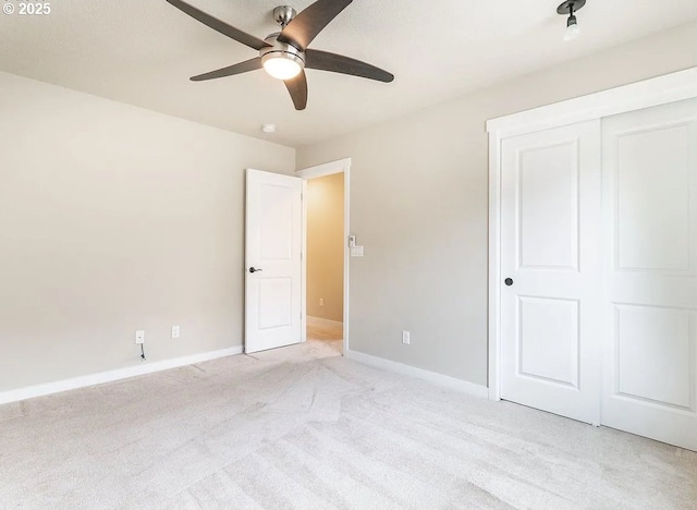 unfurnished bedroom with light colored carpet, baseboards, a closet, and a ceiling fan