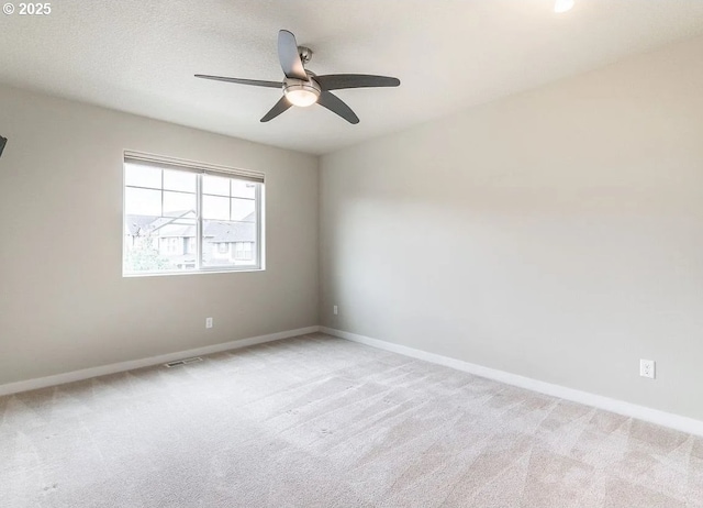 empty room featuring light carpet, baseboards, and a ceiling fan