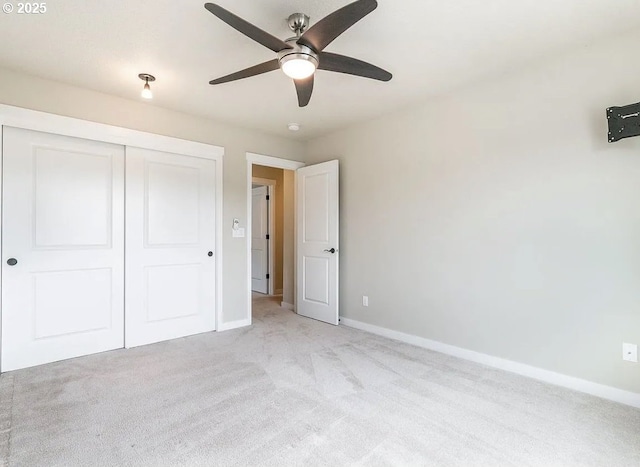 unfurnished bedroom with baseboards, light colored carpet, and a closet