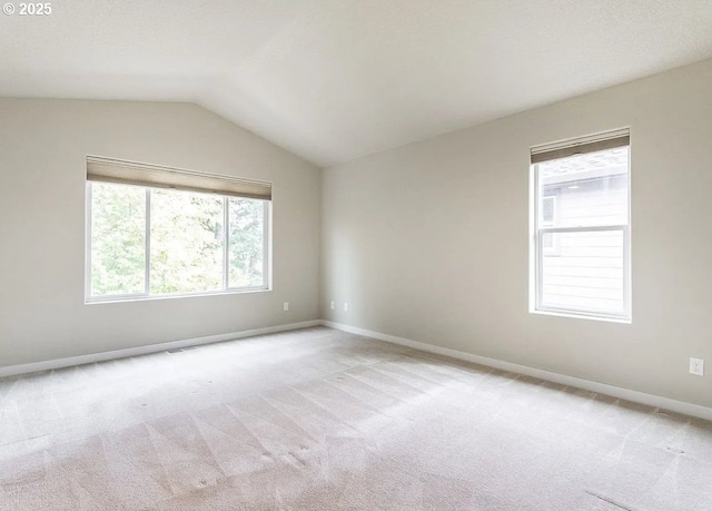 empty room with light carpet, baseboards, and vaulted ceiling