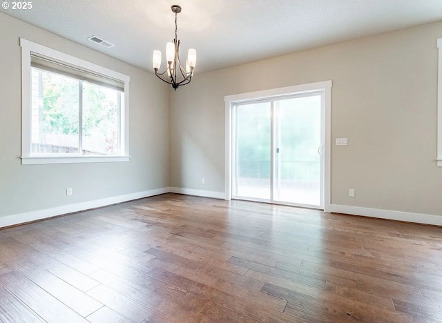 unfurnished room featuring a chandelier, wood finished floors, and baseboards