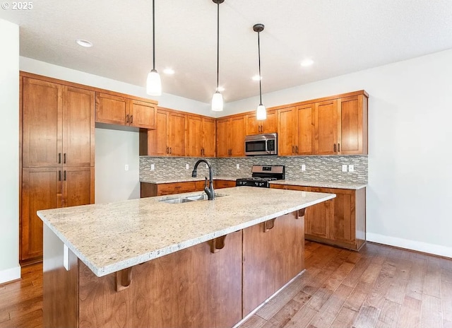 kitchen featuring appliances with stainless steel finishes, a sink, brown cabinets, and recessed lighting