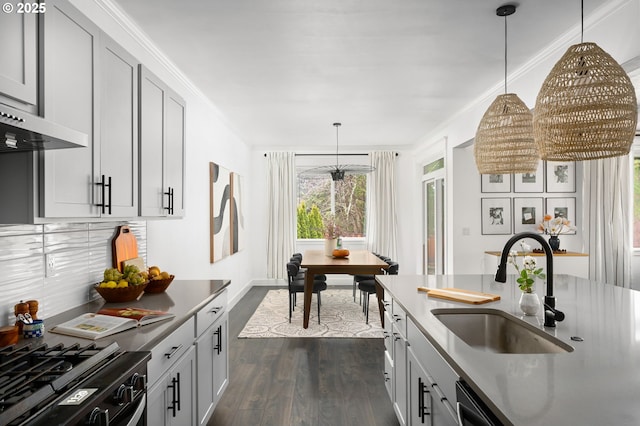 kitchen featuring decorative light fixtures, crown molding, dark wood finished floors, tasteful backsplash, and a sink