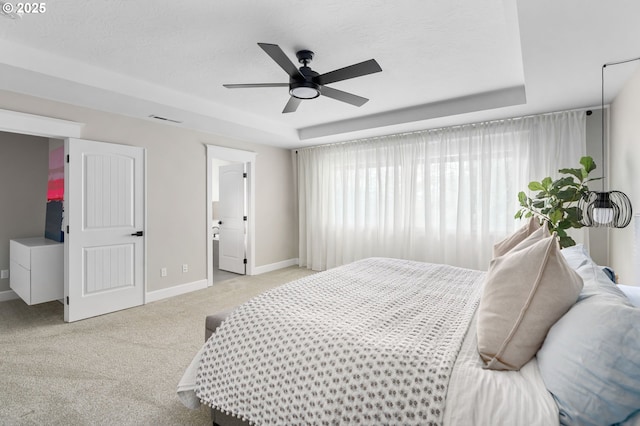 bedroom with light carpet, visible vents, baseboards, and a raised ceiling