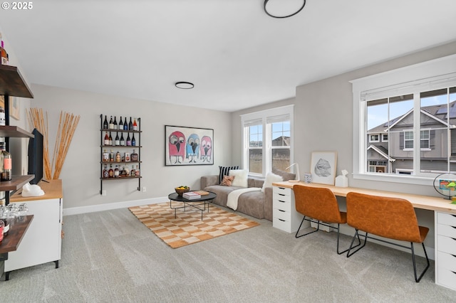 carpeted living room featuring baseboards and built in desk