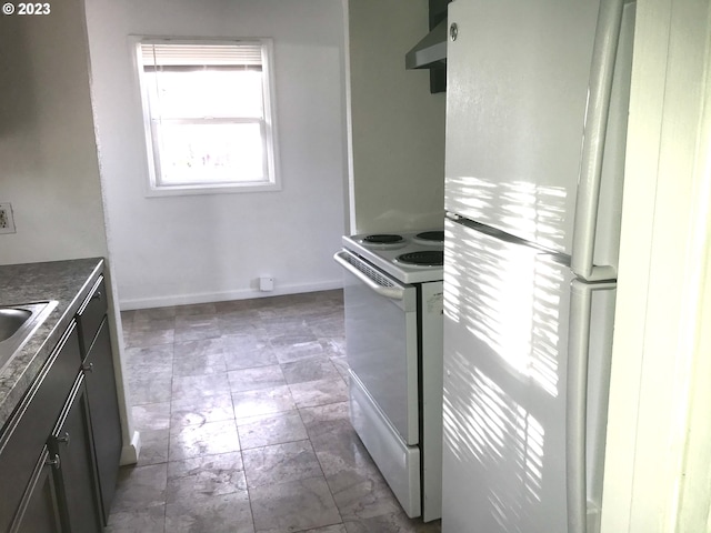 kitchen with white appliances, dark tile flooring, and wall chimney range hood