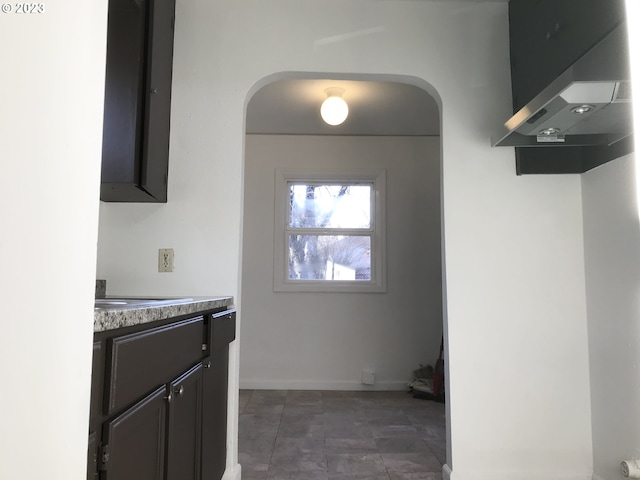 kitchen with dark tile floors and wall chimney exhaust hood