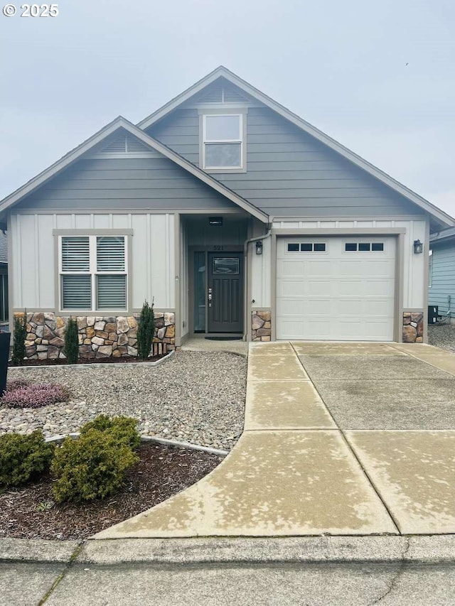 view of front of home featuring board and batten siding, concrete driveway, stone siding, and a garage