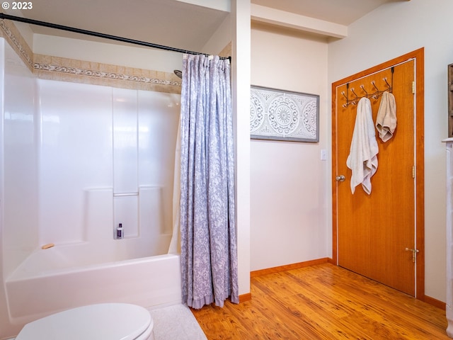 bathroom with toilet, hardwood / wood-style floors, and shower / tub combo