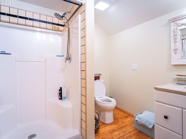 bathroom with a shower, toilet, vanity, and hardwood / wood-style flooring